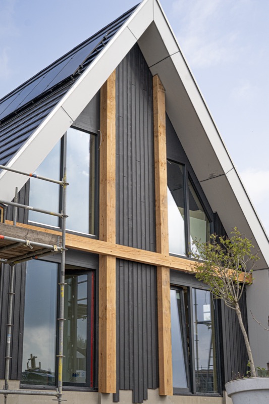 Modern huis met donkere houten gevelbekleding en zonnepanelen in aanbouw